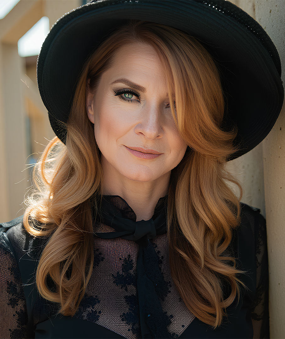 Marlies Dekkers wearing a black hat and floral lace top with a neutral background