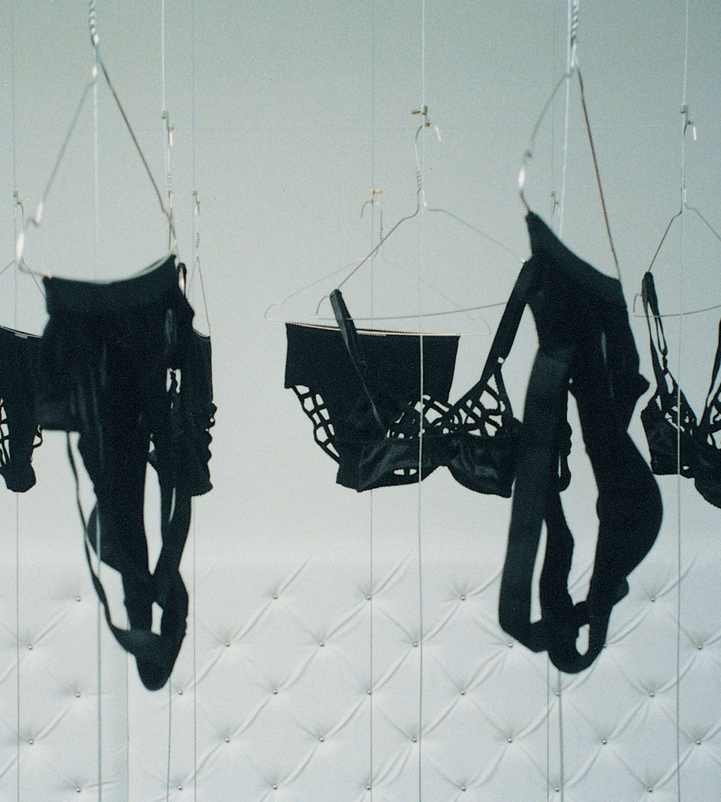 Black lingerie collection Marlies Dekkers called Spider hanging on a white quilted background