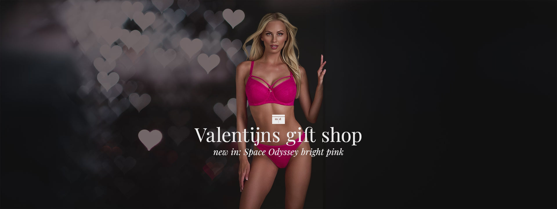 Blonde model at black background with hearts for Valentine wearing the Space Odyssey bright pink marlies dekkers lingerie set 