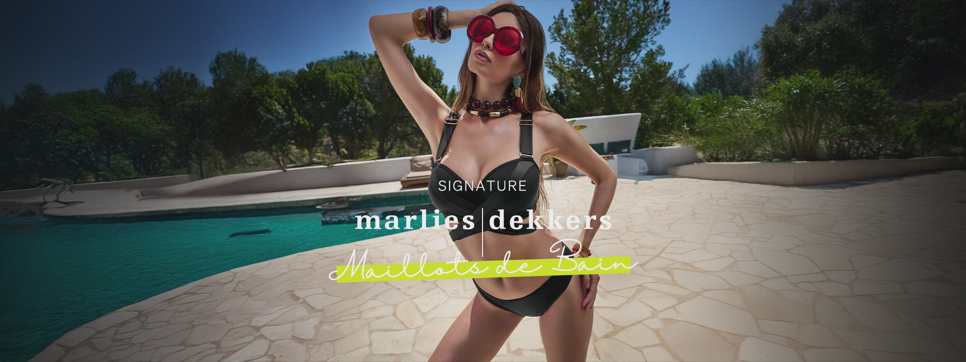 Model with brown hair wearing the Cache Coeur bikini set & bathing suit in the color black nearby the pool with red sunglasses on