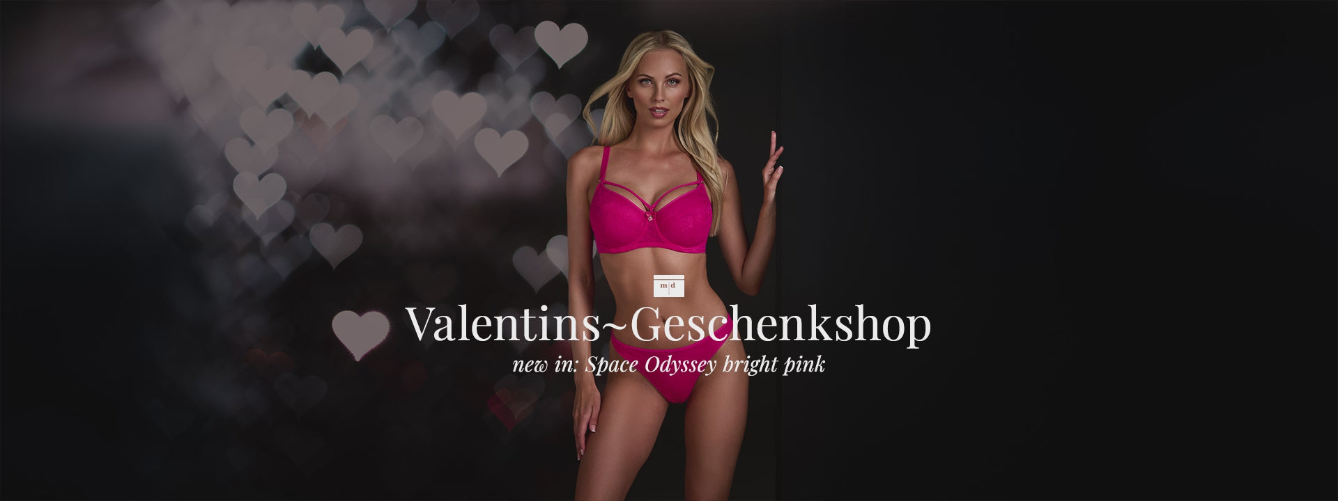 Blonde model at black background with hearts for Valentine wearing the Space Odyssey bright pink marlies dekkers lingerie set 