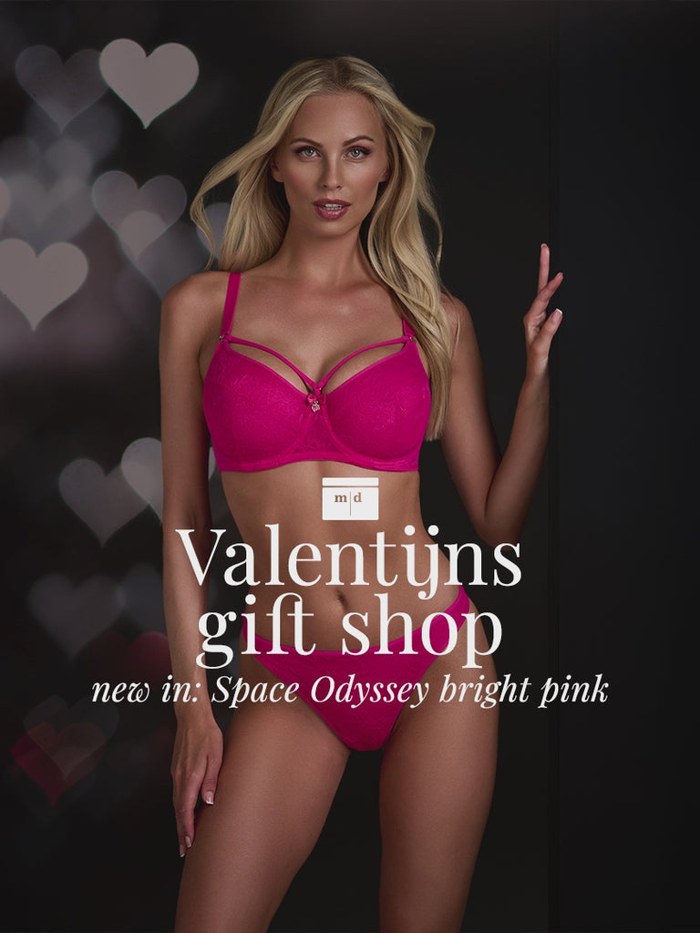 Blonde model at black background with hearts for Valentine wearing the Space Odyssey bright pink marlies dekkers lingerie set 